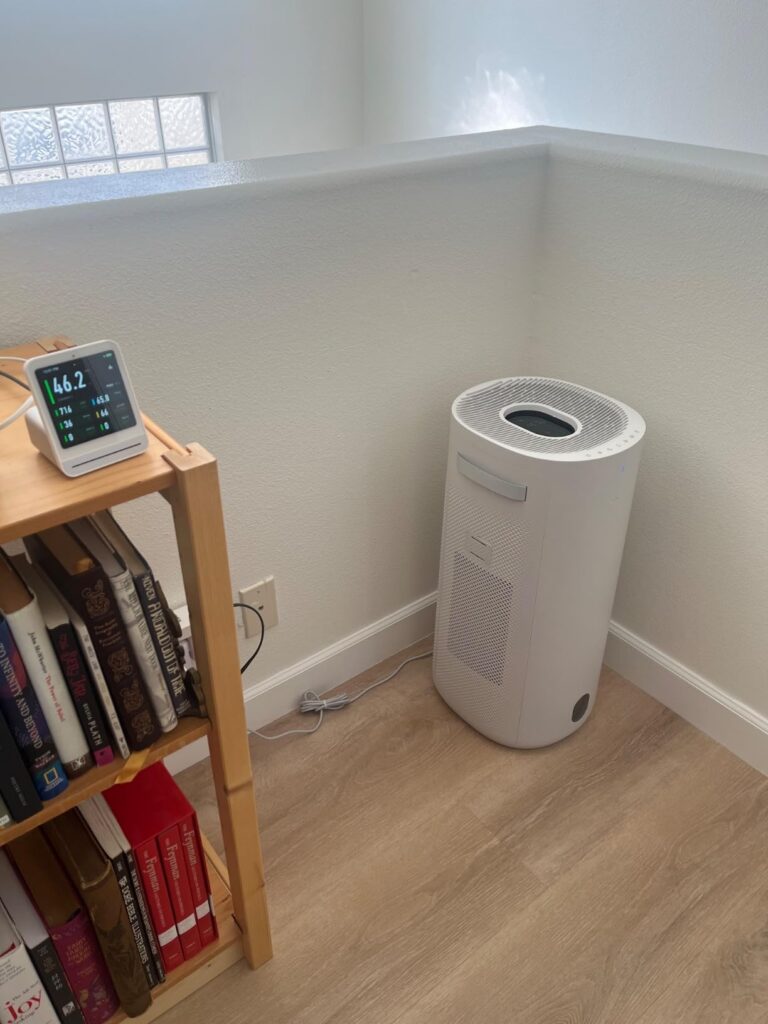Multiple air purifiers displayed in a modern living room with family members interacting in the background, showing different models in use.