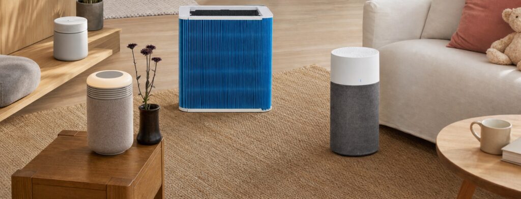A Blueair promotional banner featuring multiple air purifier models and a family living room scene with the slogan “Breathe Better with Blueair.”