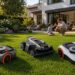 Three Navimow robotic lawn mower models displayed on a sunny residential lawn with a modern home and family in the background, presenting a clean smart lawn care product lineup.