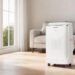 Sleek white ZAFRO smart inverter portable air conditioner standing on a hardwood floor in a minimalist sunlit modern living room.