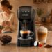 CAPXSNOB compact coffee maker brewing espresso on a warm kitchen countertop with coffee beans, capsules, ground coffee, latte drinks, and a family moment in the background.