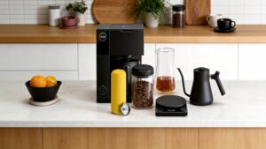 Complete Fellow coffee brewing setup featuring Aiden coffee maker, Carter Move mug, Atmos canister, Stagg kettle, Tally Pro scale, and double-wall coffee carafe arranged on a bright kitchen island.