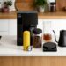 Complete Fellow coffee brewing setup featuring Aiden coffee maker, Carter Move mug, Atmos canister, Stagg kettle, Tally Pro scale, and double-wall coffee carafe arranged on a bright kitchen island.