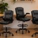 Three Brick Attic executive drafting chairs with padded ergonomic backrests, elevated seating height, footrest rings, and swivel caster bases arranged in a professional office setting.