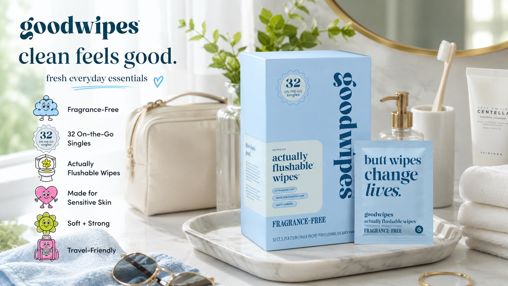 Goodwipes Fragrance-Free flushable wipes set featuring a light blue box with 32 on-the-go singles. Displayed on a marble tray with a cosmetic bag, sunglasses, and skincare products.