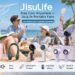 A summer outdoor group photo of a young woman in a sunny beach or park setting, closed her eyes and smiling as she holds a dark green JISULIFE neck fan around her neck. At the top-left is the product name "JisuLife" with the subtitle "Stay Cool Anywhere — JisuLife Portable Fans". Below is a blue bar with the text: "The World's No.1 Portable Fan Brand".