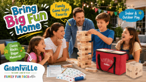 Family playing Giantville giant tumbling blocks at an outdoor game night, with a wooden tower, Family Fun Pack cards, activity sheets, large wooden die, and red carry bag for interactive indoor and outdoor play.