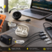 Baseus tech essentials displayed in a modern workspace, including a magnetic power bank, retractable USB-C cable, open-ear earbuds, 100W charger, portable power bank, and 10-in-1 USB-C hub with feature callouts.