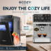 ecozy lifestyle banner featuring a smart countertop ice maker and 4-in-1 espresso machine in a bright modern kitchen, surrounded by iced drinks, espresso, latte, coffee beans, pastries, and playful feature callouts under the headline “Enjoy the Cozy Life.”