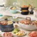 A comprehensive banner image showcasing the entire DEZIN kitchen appliance lineup arranged on a counter with various prepared foods. The text reads "DEZIN. Cook Small, Live Big," and features pointing labels like "Quick Noodles," "Steam & Savor," "Double Flavor Double Enjoyment," and "Tea Time."
