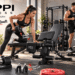 Modern home gym featuring Keppi Fitness adjustable bench, dumbbells, barbell clamps, and stair stepper, with two athletes performing strength and cardio workouts alongside “Own Your Strength” callouts and red graphic arrows.
