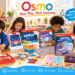 Four children sitting together around a table joyfully engaging with various Osmo educational game kits, including Pizza Co., Genius Starter Kit, Detective Agency, Math Wizard, and Coding. Colorful text bubbles highlight "Real Play, Real Learning," "Fun Educational Games," and "Hands-On Math, Coding & Creativity."