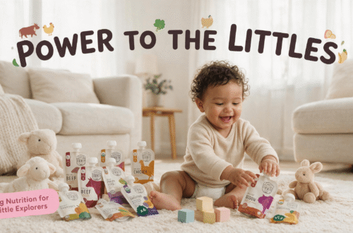 A wide shot of a smiling baby with curly hair sitting on a shaggy rug in a living room, surrounded by multiple Serenity Kids baby food pouches of different flavors like Beef, Chicken, and Bison, and several plush lamb and rabbit toys. Across the top, the text "POWER TO THE LITTLES" is written with small animal illustrations. A pink text box in the bottom left corner reads "Big Nutrition for Little Explorers".