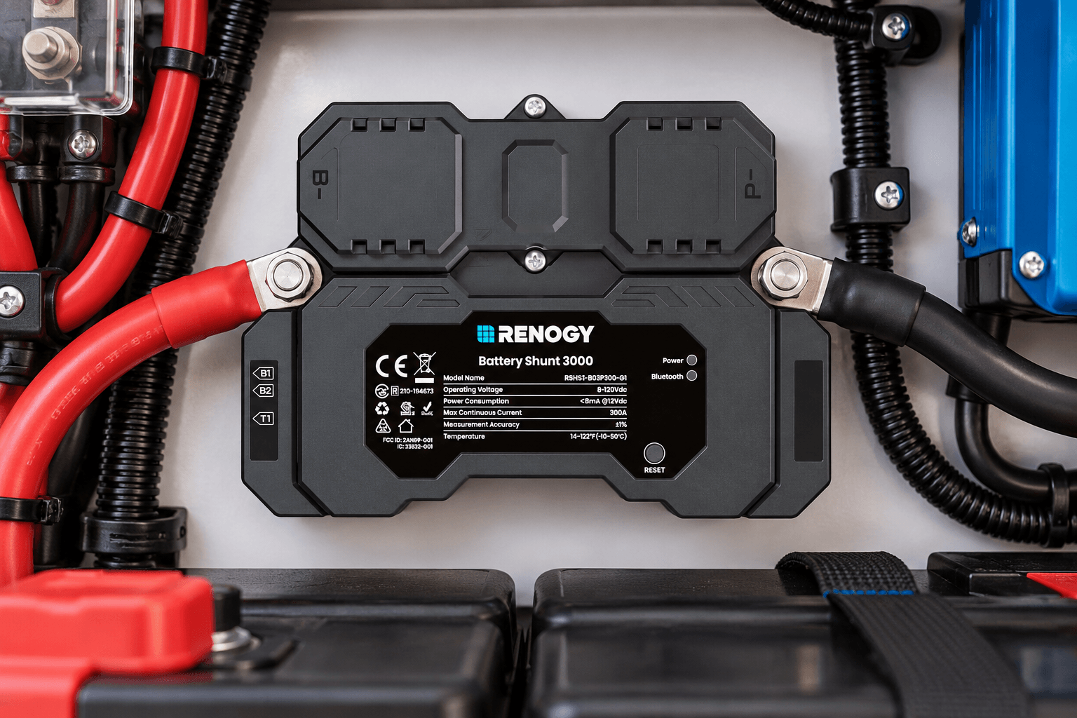 Renogy Battery Shunt 3000 installed in an organized RV battery compartment, featuring a rugged black housing, Renogy branding, labeled terminals, and heavy-duty power cables. The close-up highlights its integration into an off-grid battery monitoring system.