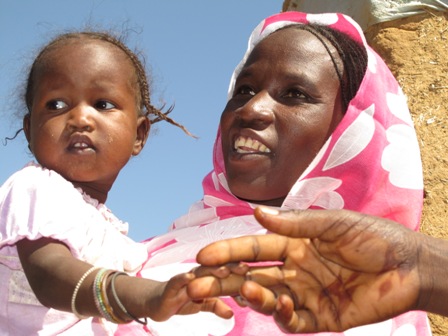 Maryam Gado’s daughter holds the hand of a public health promoter. Photo by Elizabeth Stevens/Oxfam.