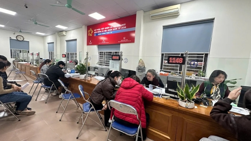 Cán bộ BHXH quận Nam Từ Liêm đang hướng dẫn người dân hoàn tất hồ sơ thủ tục BHXH