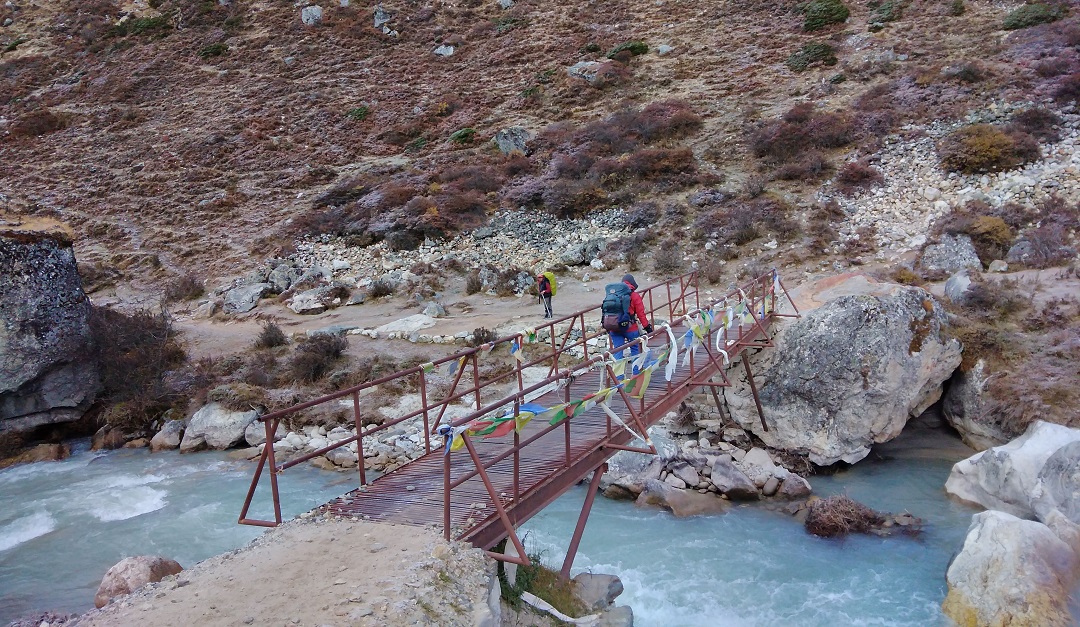 Trekker crossing a bridge near Pheriche