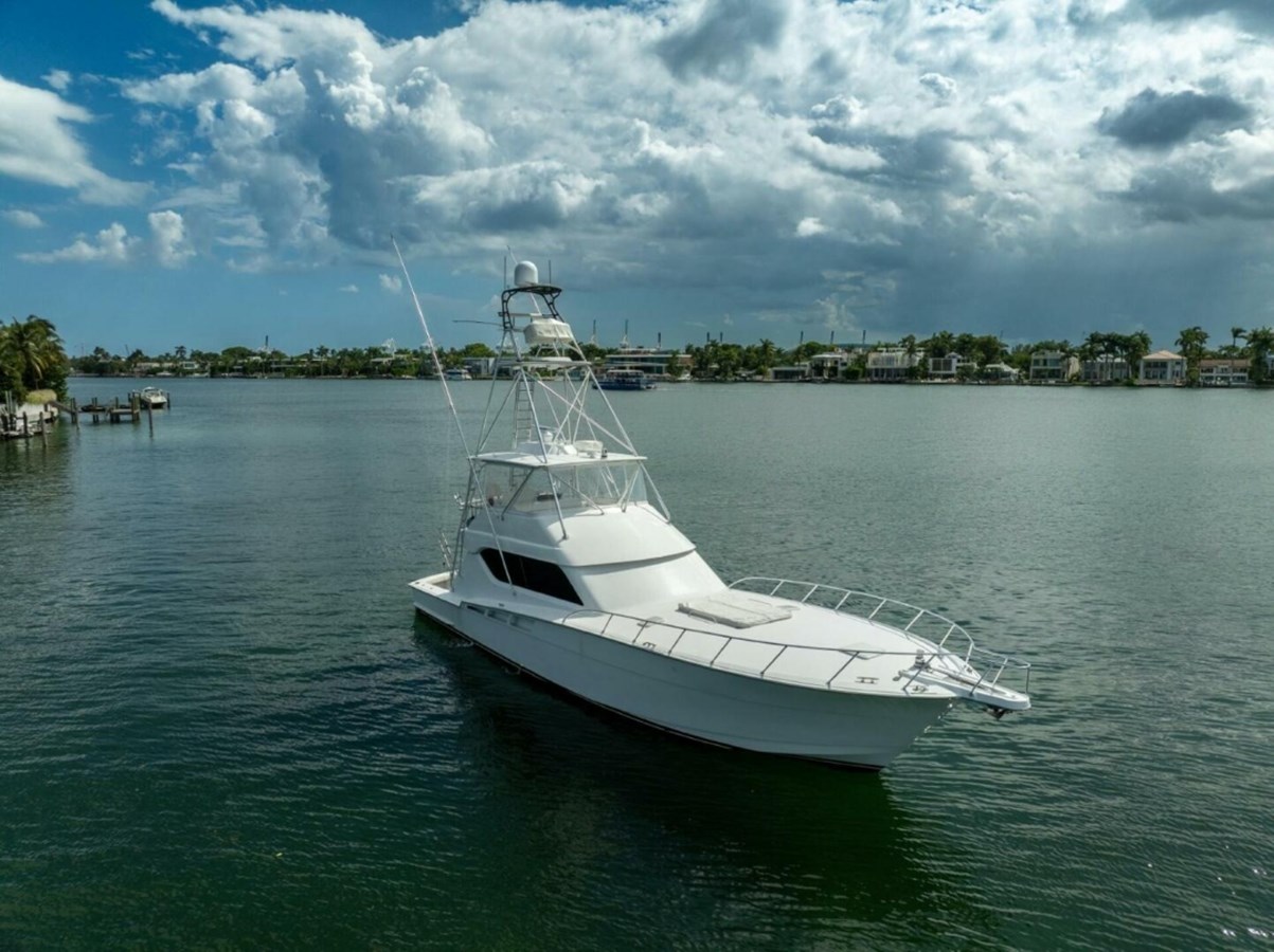 2005 Hatteras 60 Convertible yacht on calm water under cloudy sky.