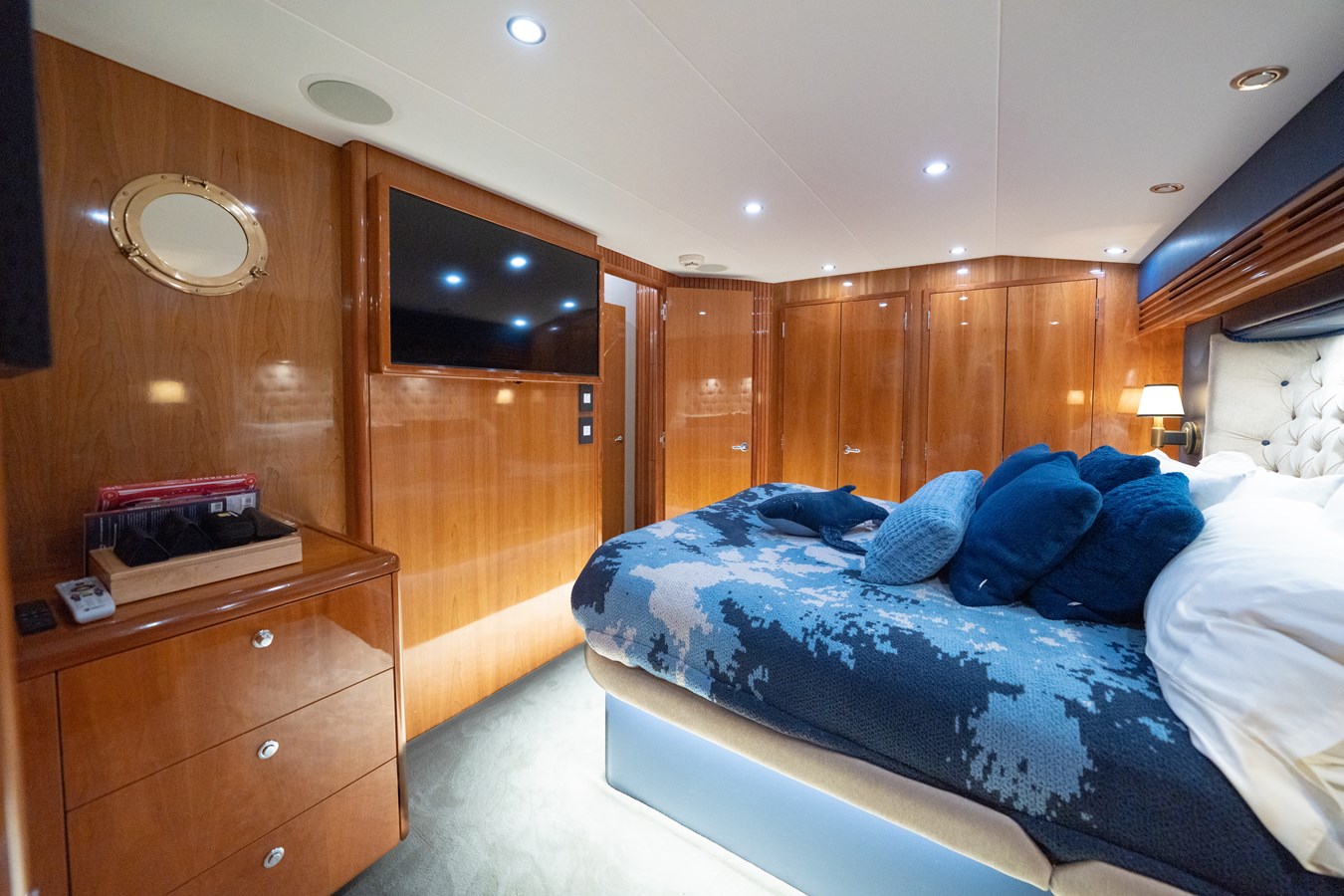 Luxurious cabin interior of 2005 Hatteras 60 Convertible yacht with wood paneling and plush bedding.