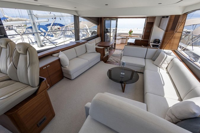 Luxurious 2025 Princess F65 yacht cruising in serene blue waters near a lush green island.