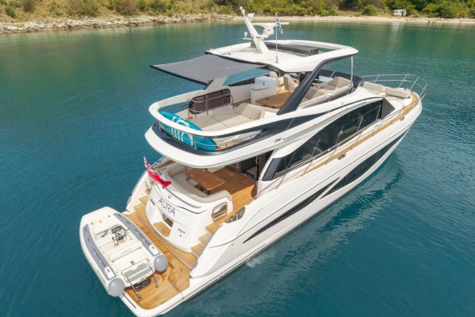 Luxurious 2025 Princess F65 yacht cruising in serene blue waters near a lush green island.