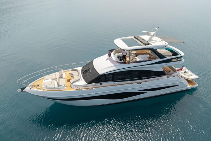 Luxurious 2025 Princess F65 yacht cruising in serene blue waters near a lush green island.