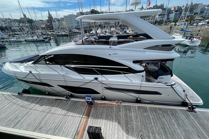 Luxury 2020 Princess F55 yacht docked in marina under blue sky.