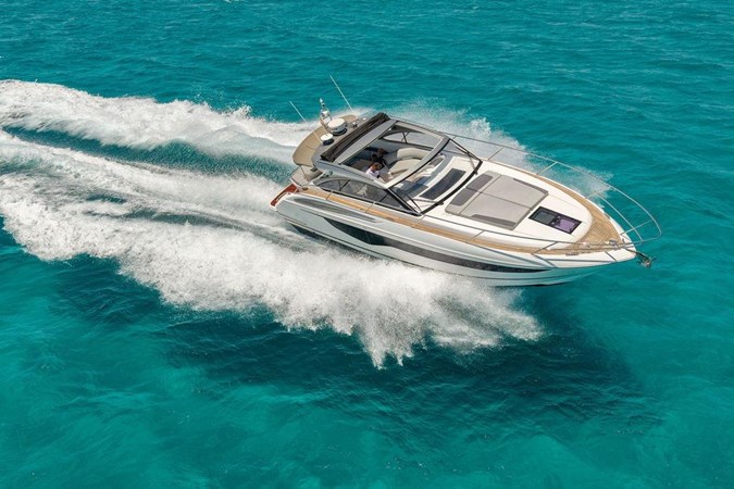 2018 Princess V40 yacht cruising on clear blue waters near a scenic coastline.