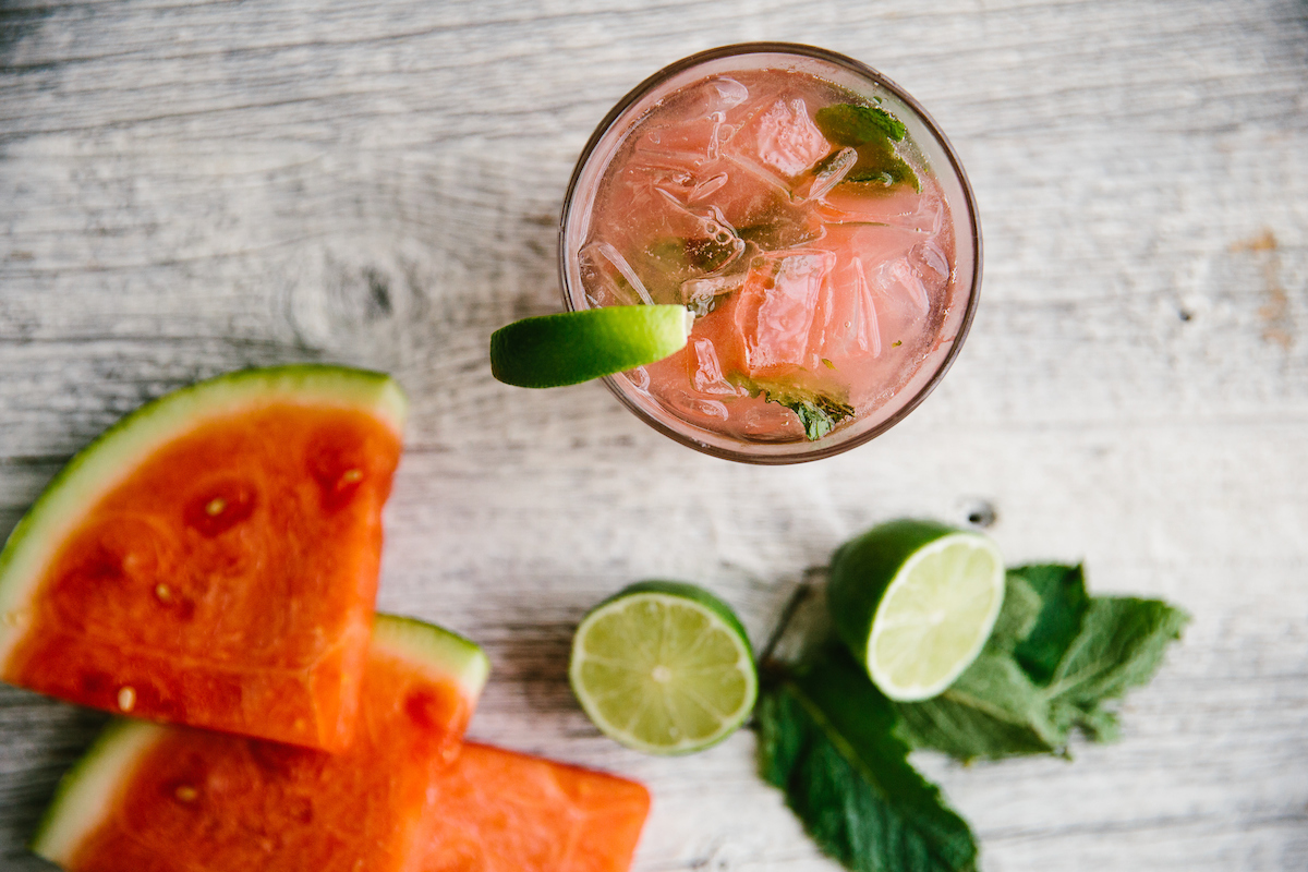 overhead watermelon cocktail with limes and watermelon ingredients surrounding it