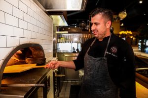 Chef Joe tends to the pizza oven at Antico Posto