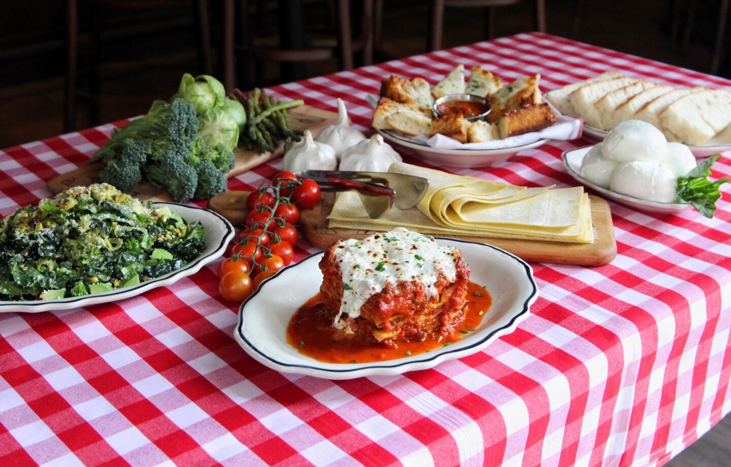 burrata lasagna, green chopped salad and tuscan cheese bread on table with ingredients