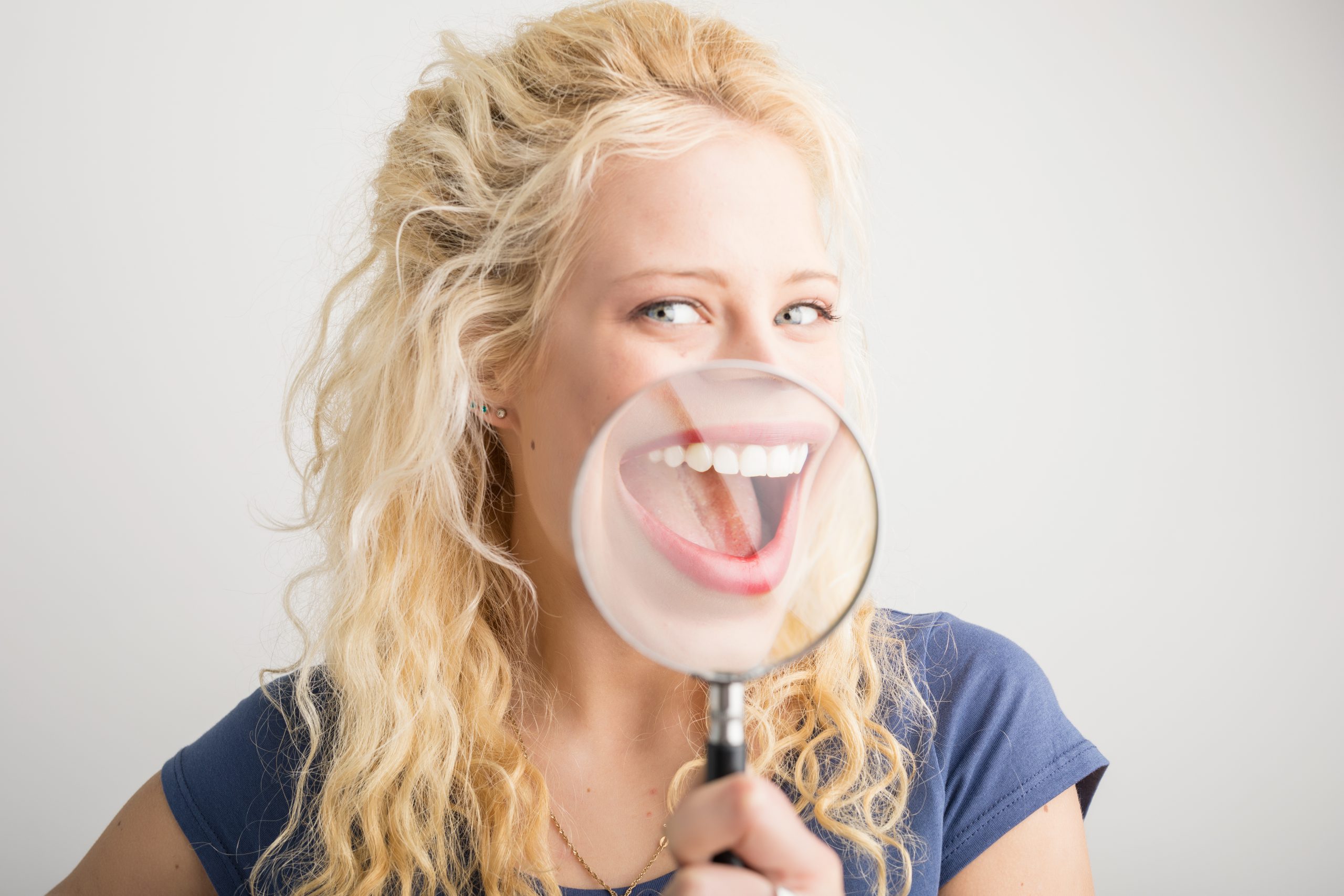 Woman showing her smile through magnifying glass