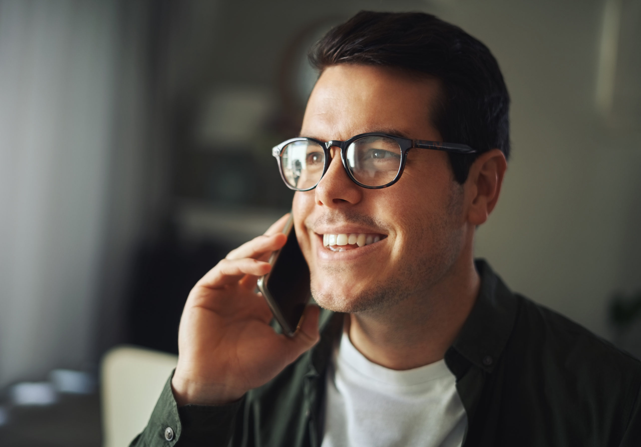 Smiling handsome man wearing black eyeglasses talking on a mobile phone