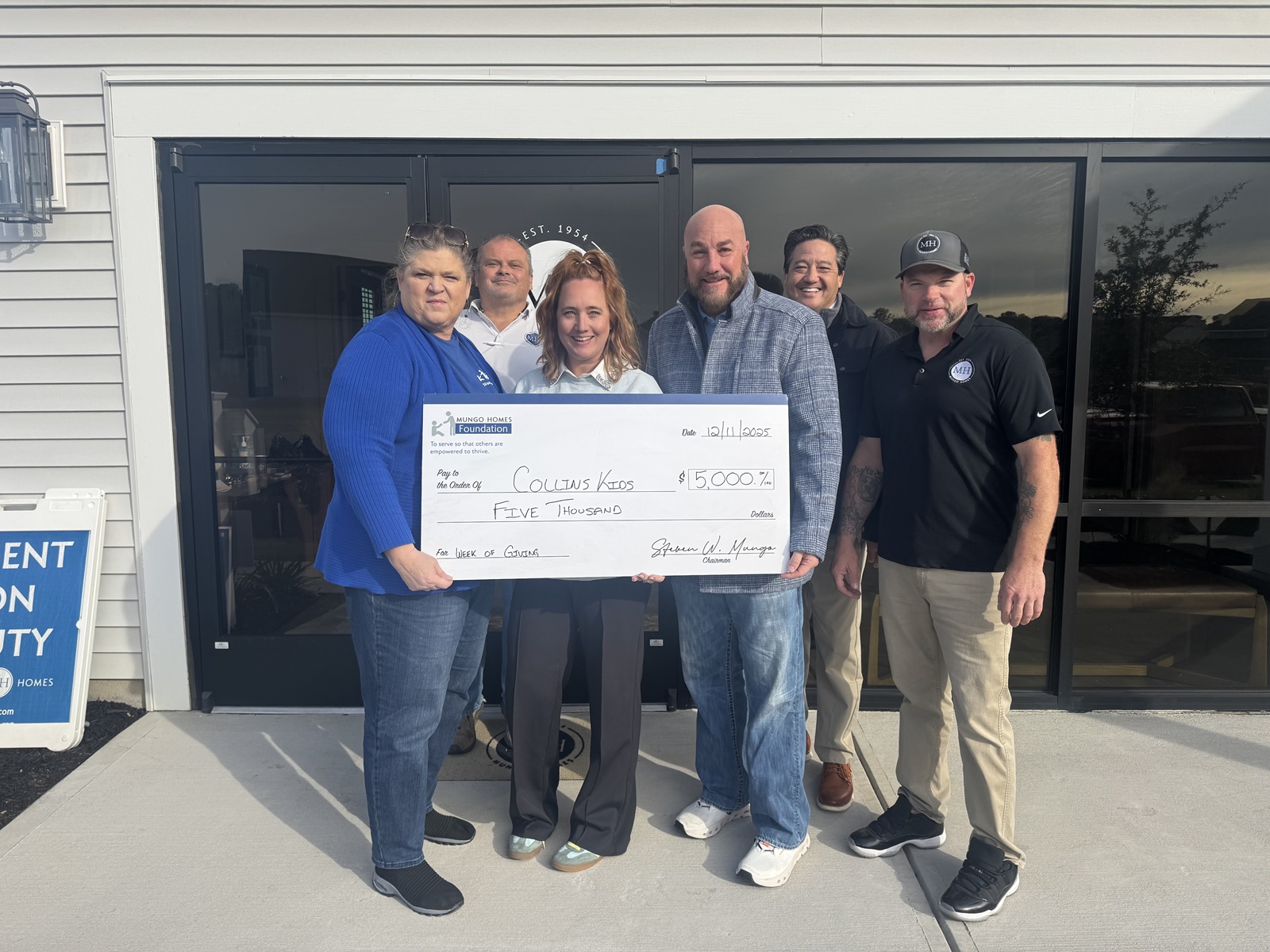 A group of people holding a giant check for Collins Kids.