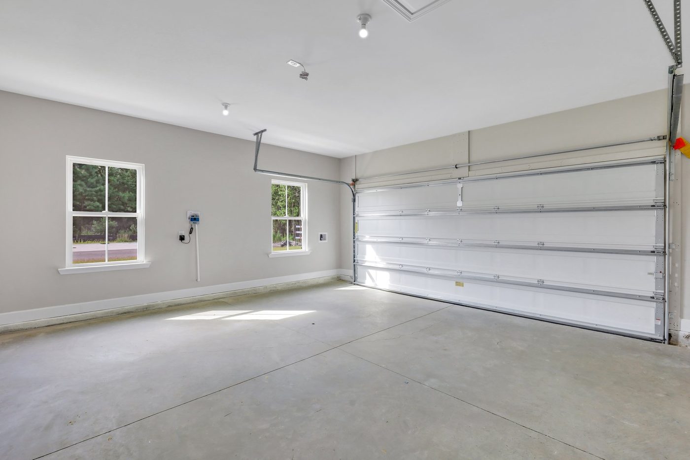 Finished garage with painted walls, windows, lighting, and garage door opener in a new home
