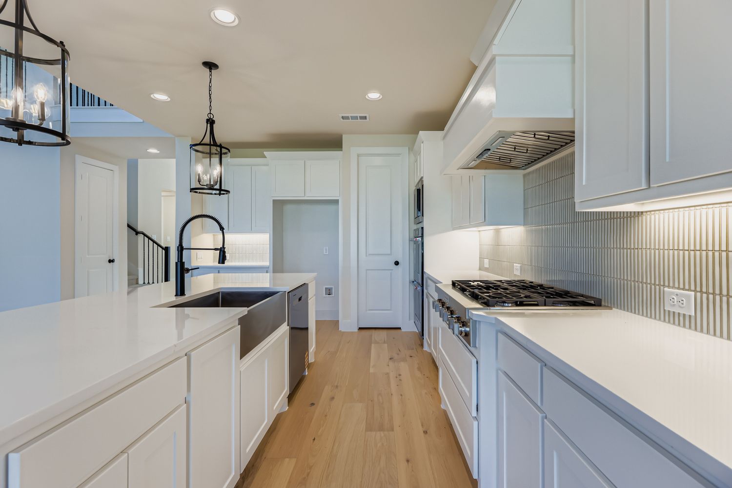 Kitchen with apron-style farmhouse sink, gas burner stove, and two chandeliers over the island