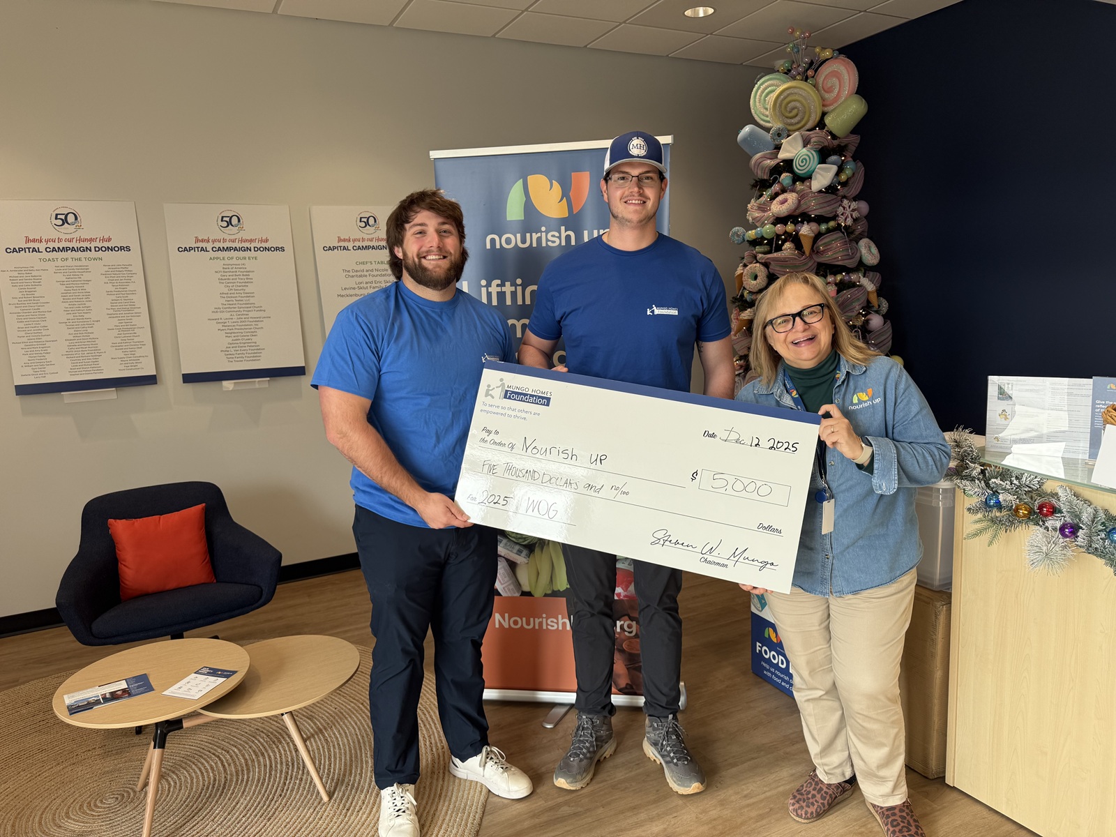 Three people smile with a giant check for Nourish Up.