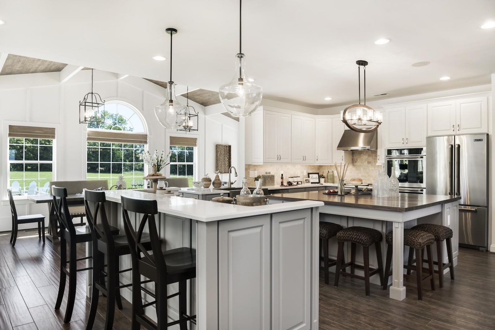 Spacious, modern kitchen with two-tone island, white cabinetry, stainless steel appliances, and large windows letting in natural light.