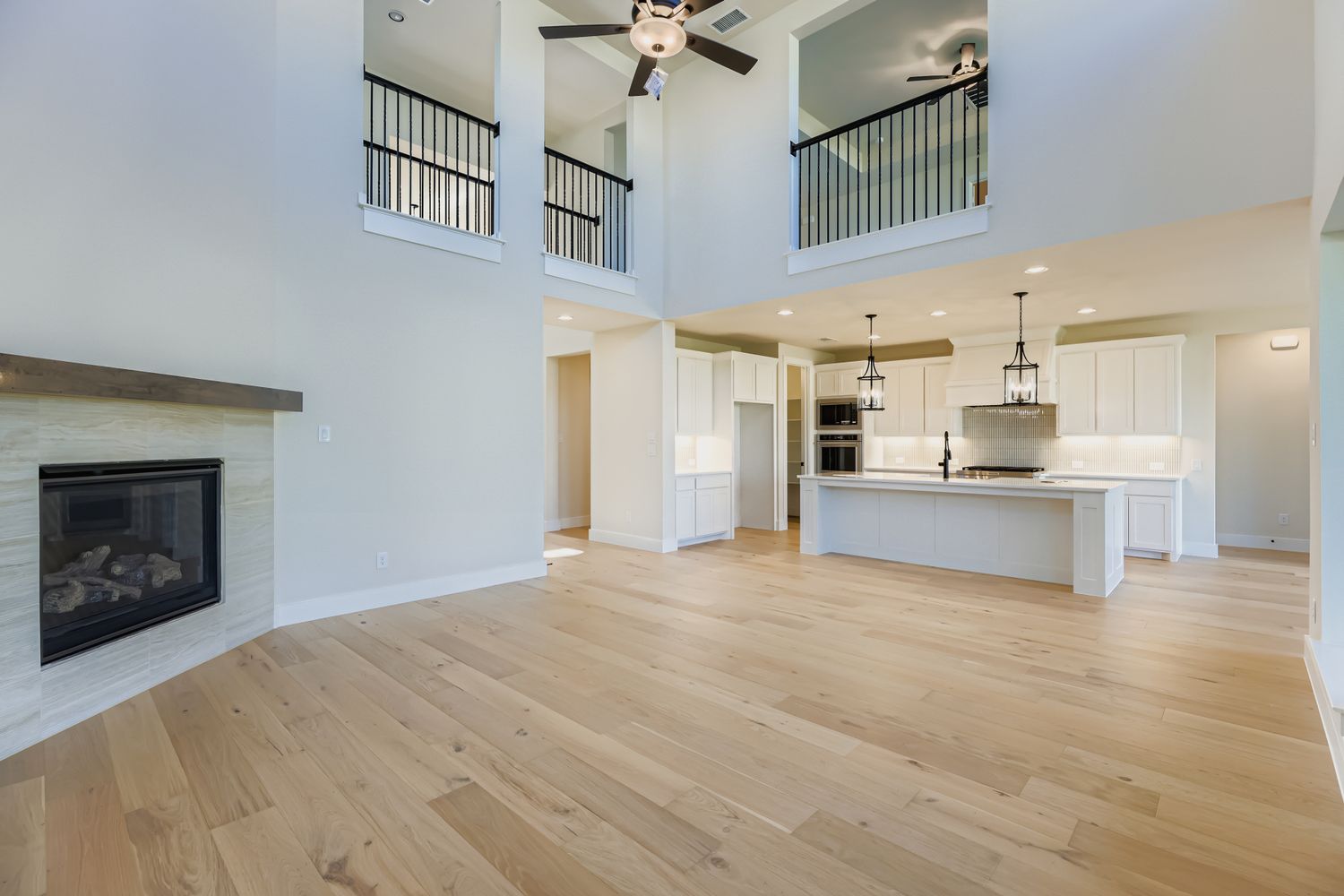 living room with fireplace opened up to second floor railing, and kitchen
