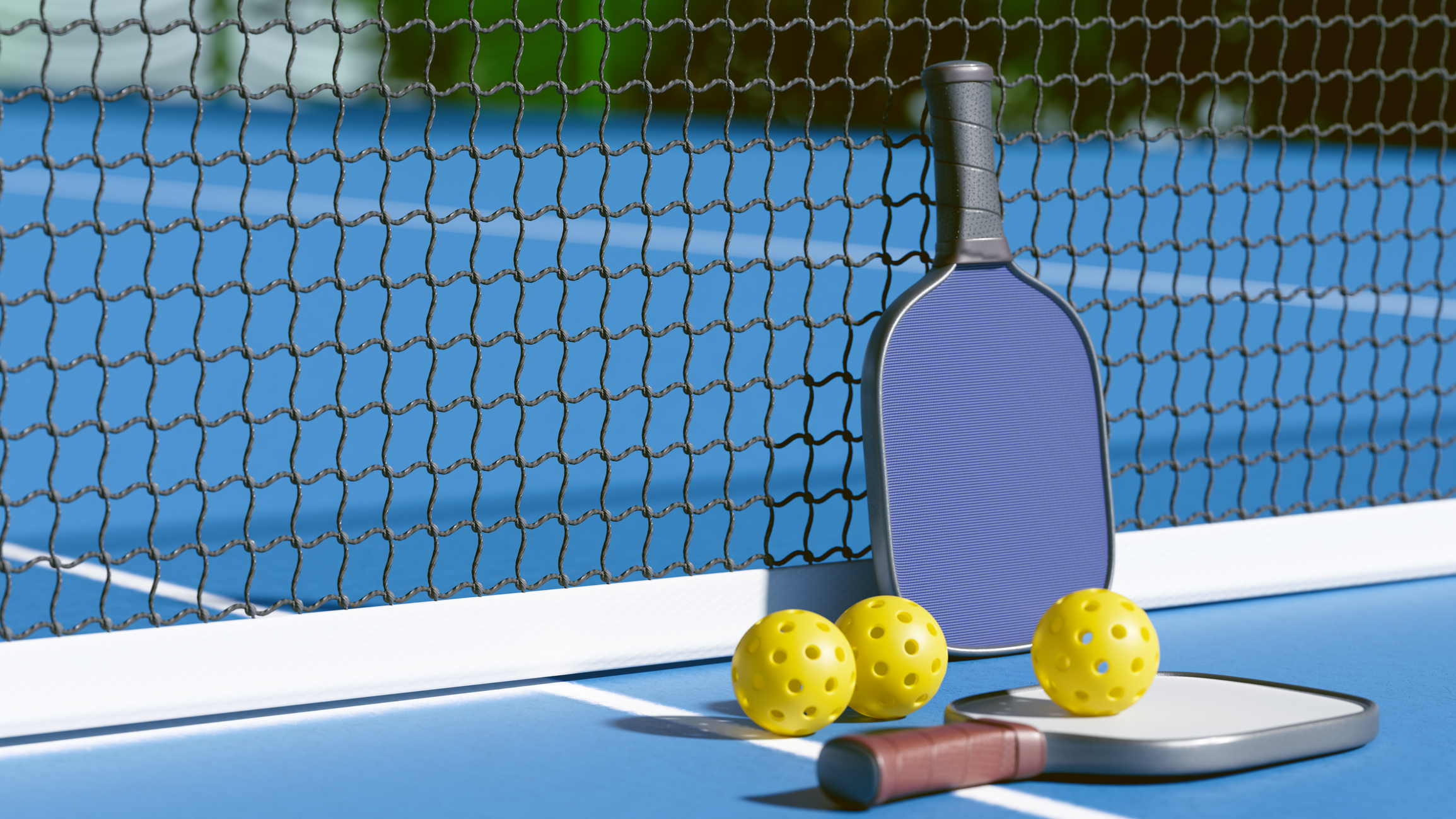 Pickleball paddles and balls next to a net on top of a blue court with white lines