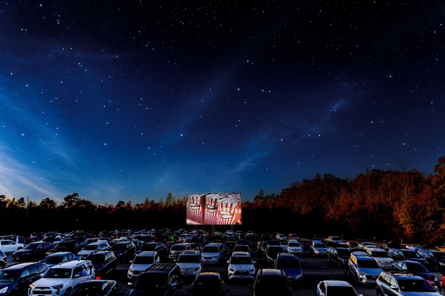 Cars parked at a drive-in movie theater at night