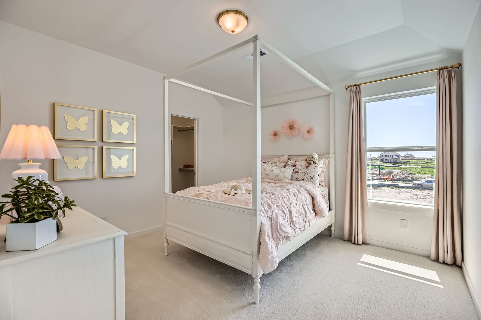 Adolescent bedroom featuring a canopy bed, with pink accents of flowers and butterlifes on the wall. Full size bed in center of room.