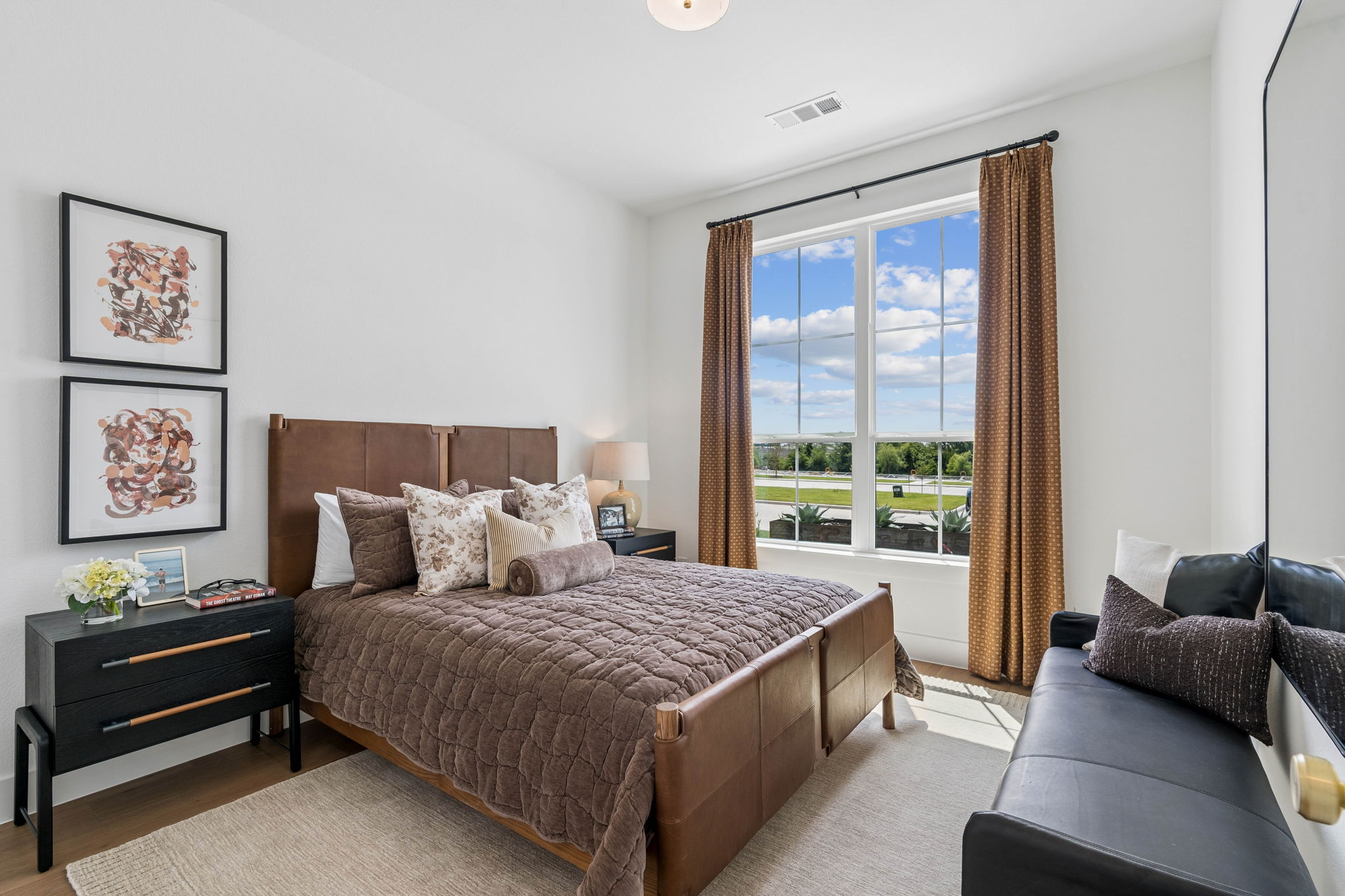 Warm-toned accessorized guest bedroom with large window flooding in light