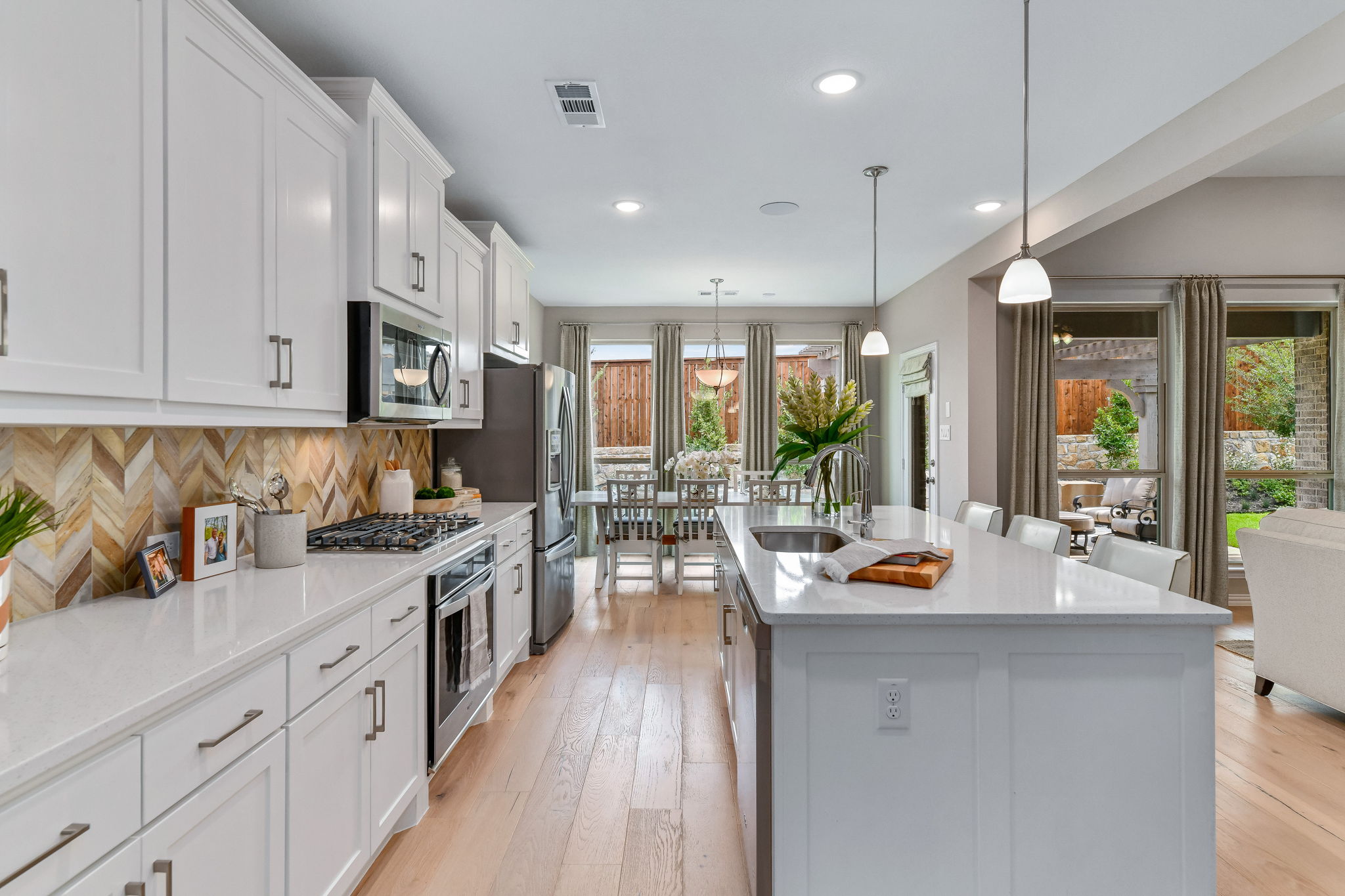 Expansive kitchen that leads to dining room, surrounded by floor-to-ceiling windows
