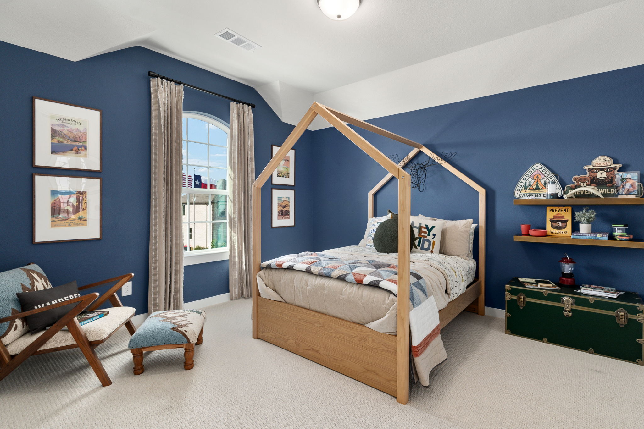 Kid's nature themed bedroom with blue walls and a home-structured bed frame.