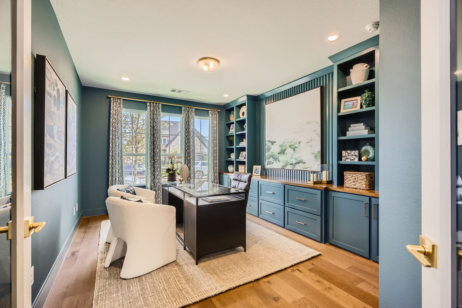 Spacious study with coporate feel desk, and built-in shelving from floor to ceiling including shiplap walls and windows along the back. French windowed doors open to this room.