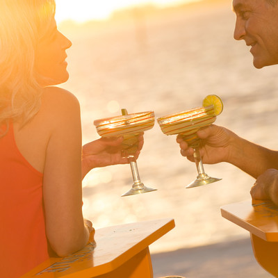 Man and woman on the beach with drinks in their hands