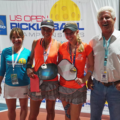Four people holding Pickleball Paddles