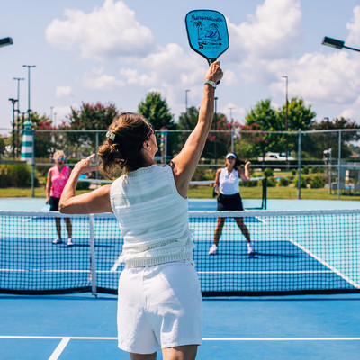 Women jumping up in the air with a pickleball paddle