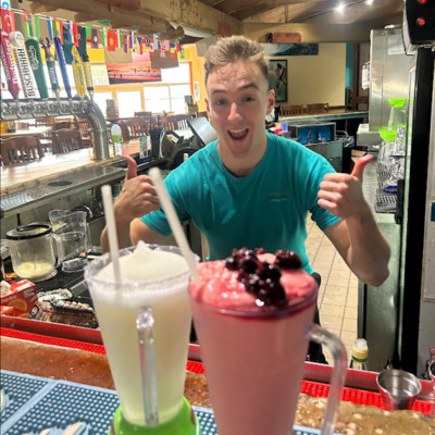 Photo of smiling bartender giving thumbs up behind two blended smoothies